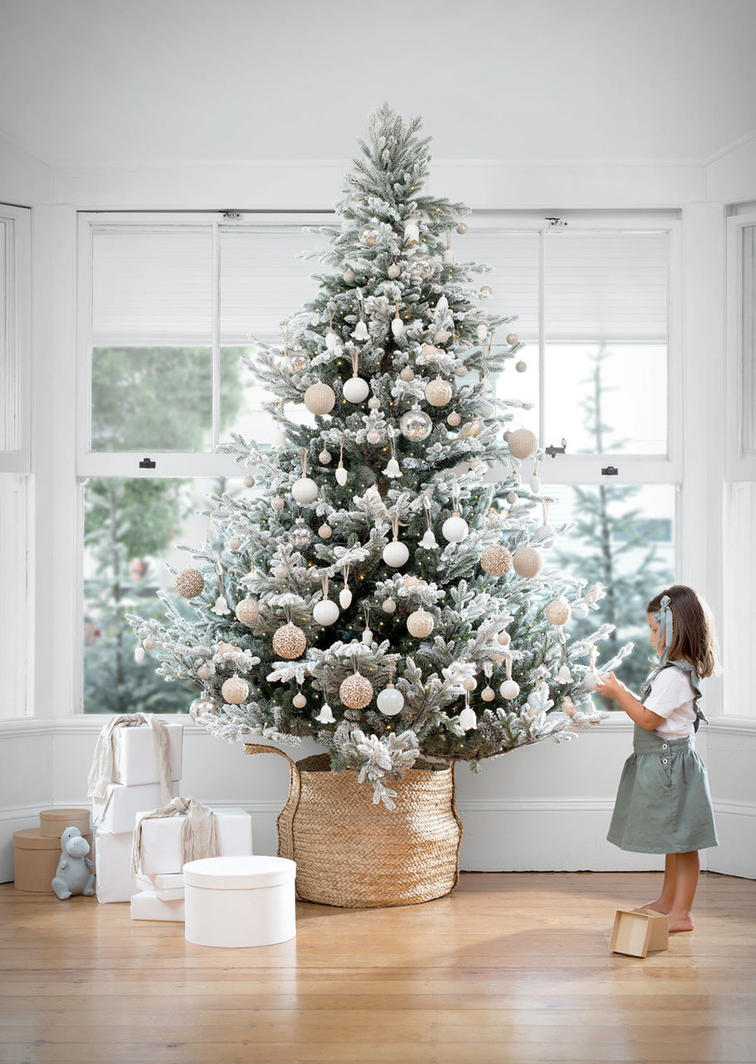 Large Christmas tree decorated with gold, silver and white luxurious decorations with a small girl